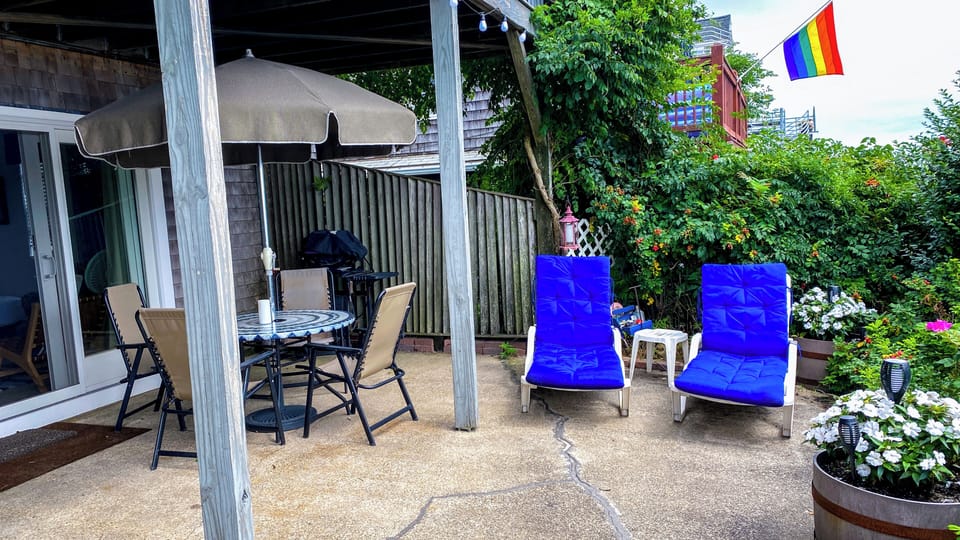 Private patio with dining set, lounge chairs, grill & lush blooms