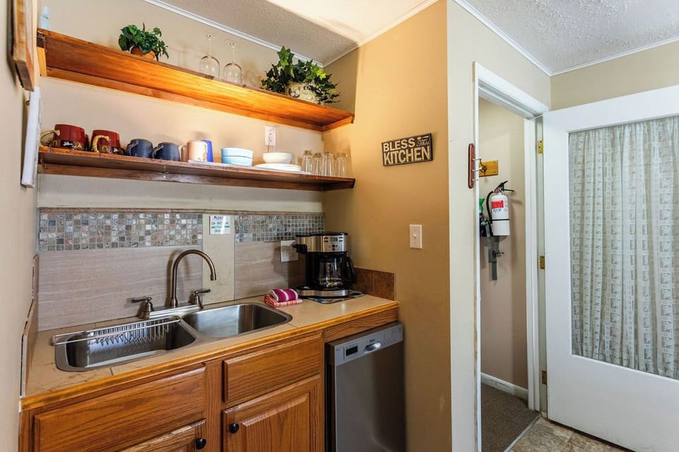Your cozy kitchenette features warm wood cabinets, open shelving for your belongings, and a coffee maker for morning brews.