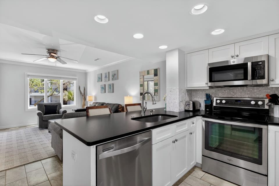 Bright open-concept living with a modern kitchen featuring sleek black granite counters, stainless appliances, and a view to your comfortable lounge area.