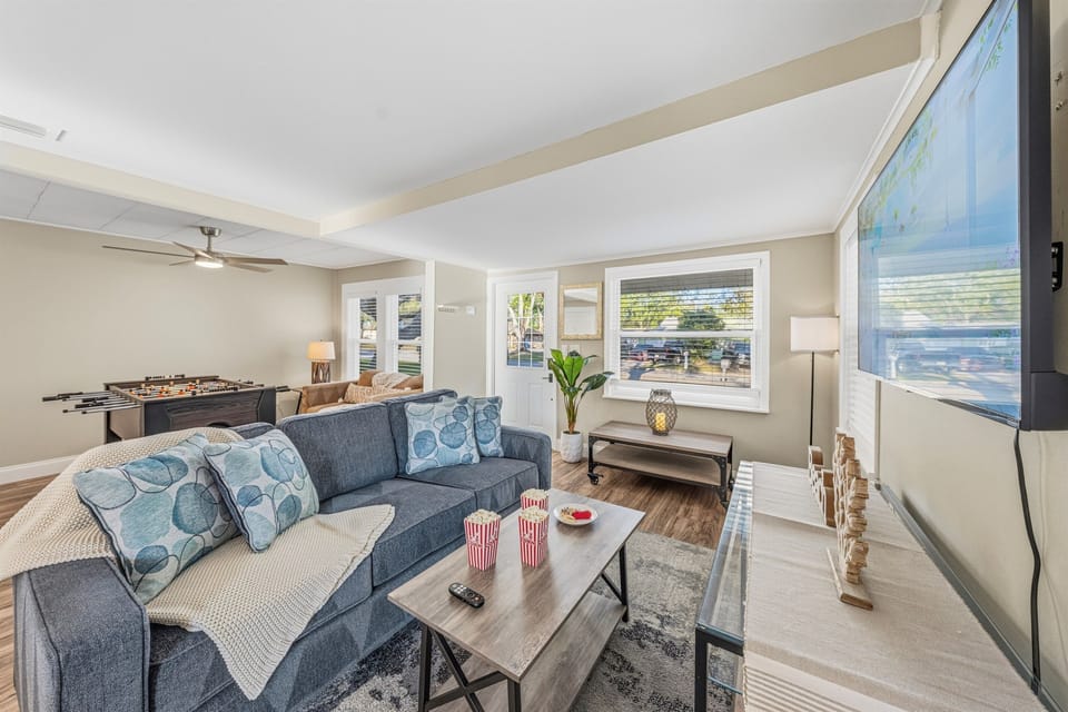 Bright and cozy living room with comfortable seating, large TV, and a fun foosball table for entertainment.