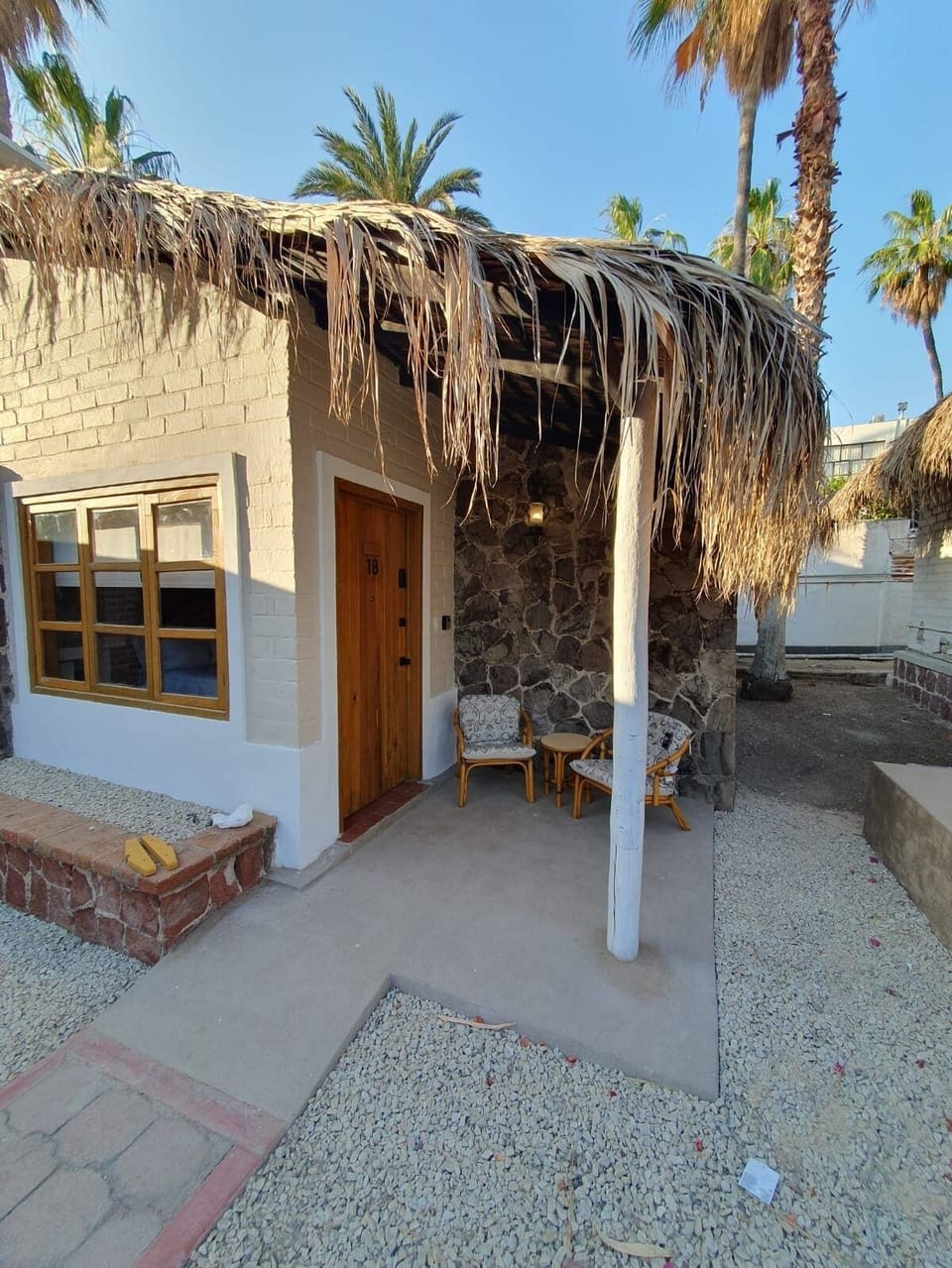Nuestra cabaña ofrece un encantador espacio exterior con techos de palma y un área de descanso con sillas y mesa. Perfecto para relajarse y disfrutar de la tranquilidad del entorno natural y la brisa fresca.