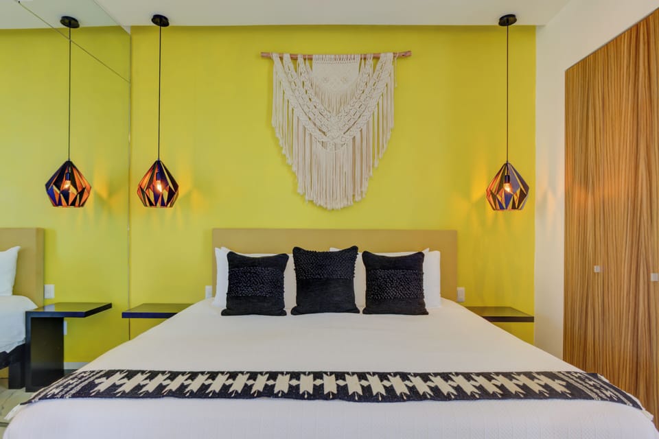 Fall in love with our boutique layout, centering a plush queen bed against a bold chartreuse accent wall decorated with an intricate macrame hanging and geometric copper pendant lighting.