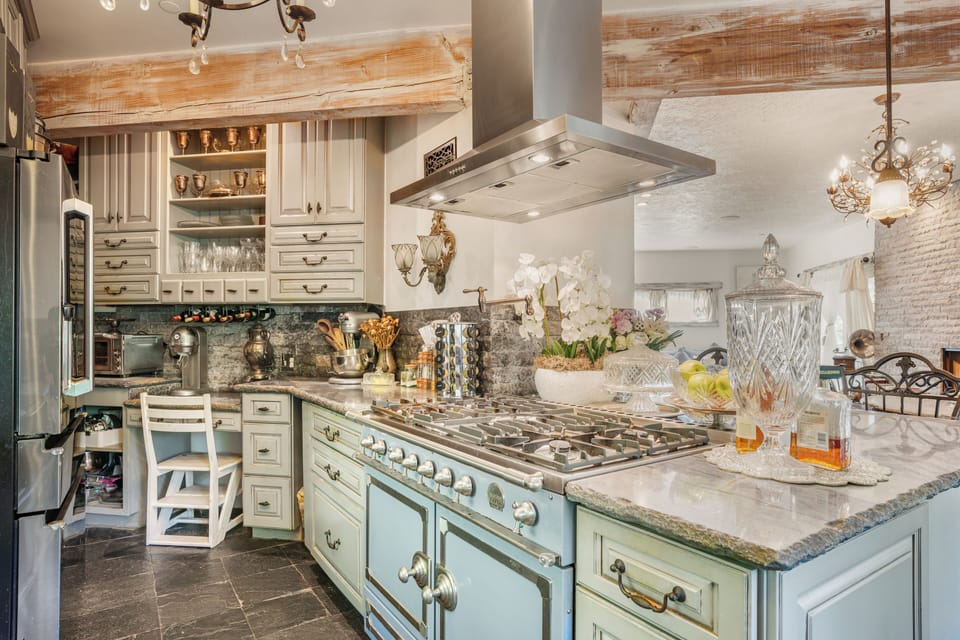 Chef's kitchen with a blue range stove and marble countertops