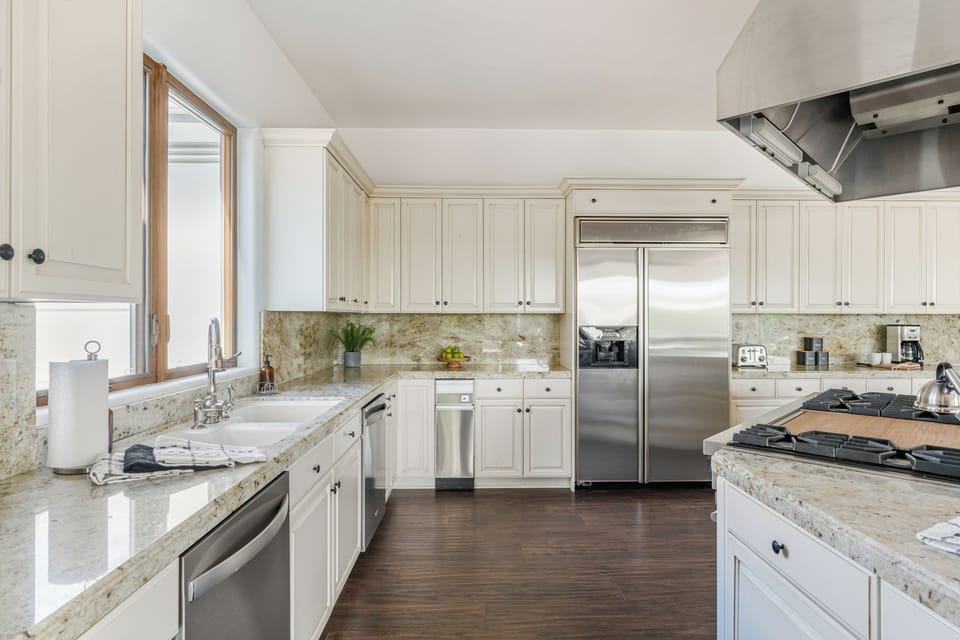 Bright, fully stocked kitchen with granite counters, stainless steel appliances, and plenty of space for cooking and gathering.