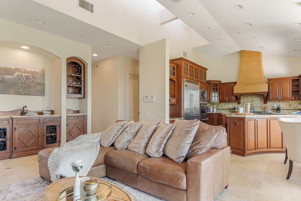 Third living room with a leather couch, TV and outdoor views.