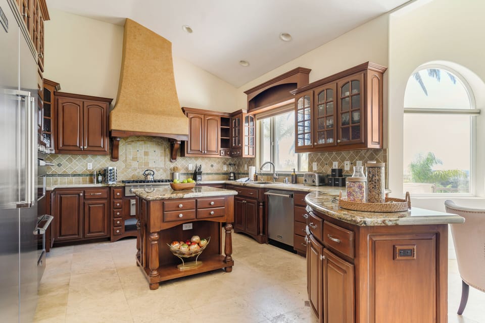 Warm, traditional kitchen with rich wood cabinetry, granite counters, and a spacious central island.