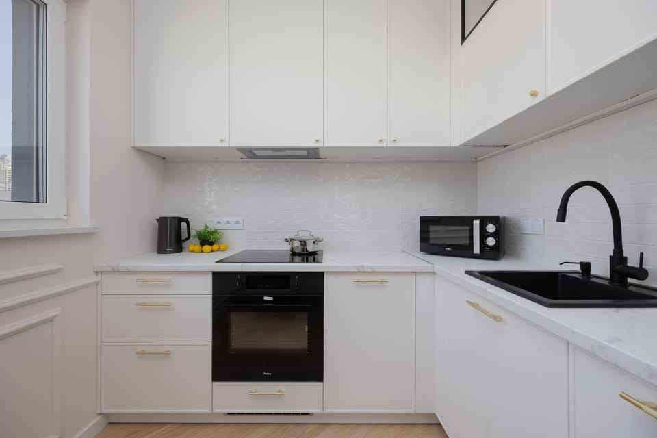 Another angle of the kitchenette highlighting the sink, stovetop, and white tiled backsplash. The layout is compact yet efficient.