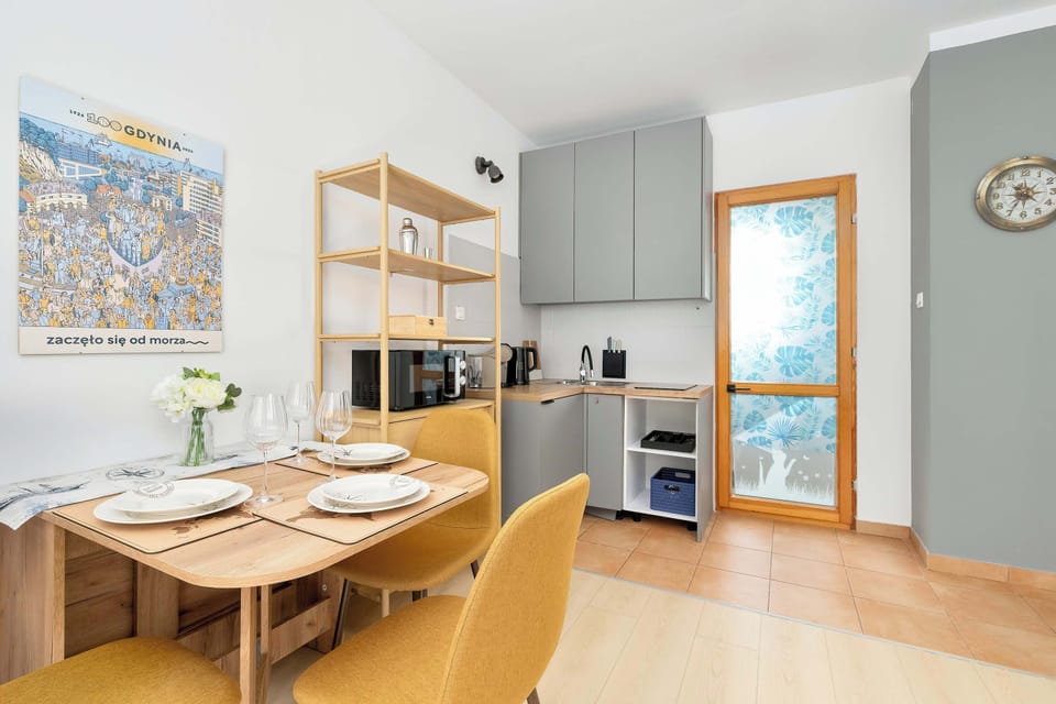 The kitchen and dining area in the open studio, featuring a compact kitchenette with cabinets, microwave, induction hob, and a dining table with chairs. The space is practical and well-organized for everyday living.