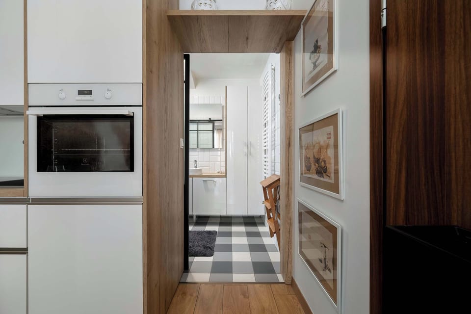 A hallway transition shows the view from the entrance toward the bright studio space. Framed artwork on the wall adds a personal touch to the entryway.