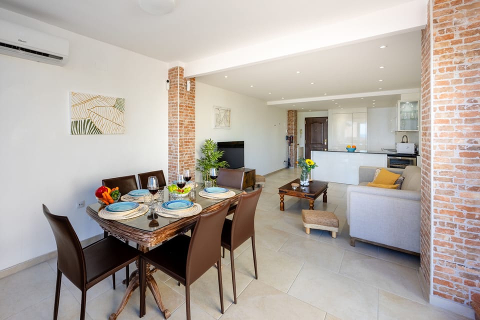 Open-plan living and dining area with rustic brick accents and modern furnishings.