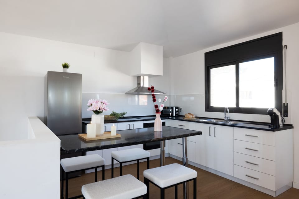 Modern kitchen with sleek black countertops and island seating for four.