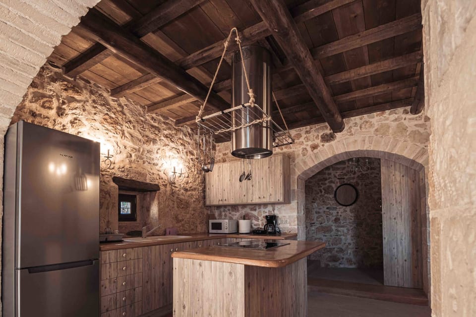 Main Villa: Kitchen space set under wooden beams, combining rustic materials with a practical layout for everyday cooking.