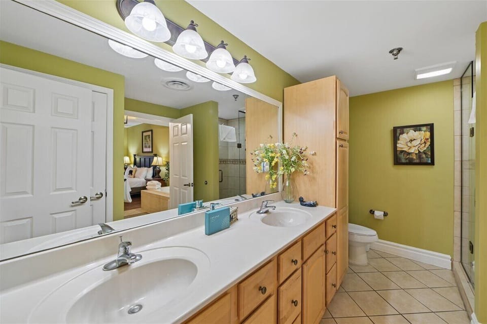 Step into your spacious bathroom with dual sinks, ample storage, and cheerful green walls that create a refreshing morning routine.