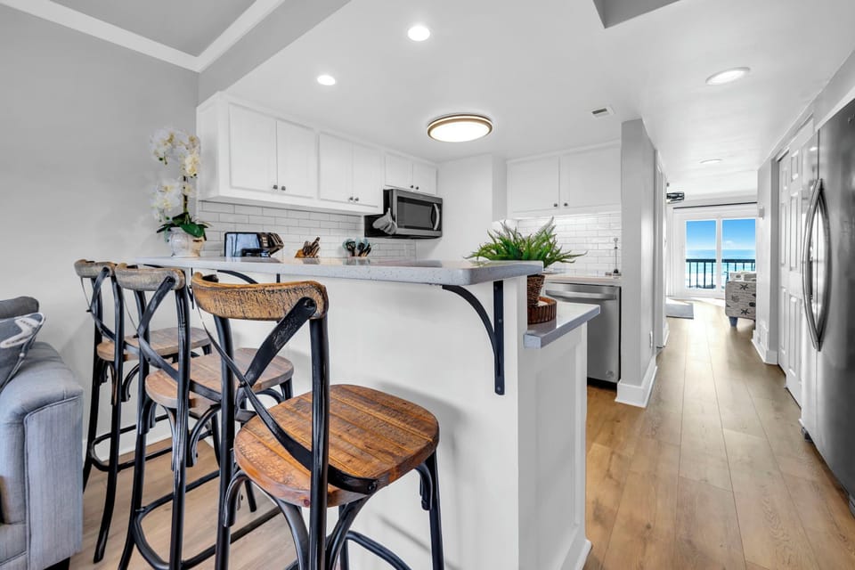 Your fully equipped kitchen features modern appliances and a breakfast bar where you can enjoy morning coffee while ocean breezes flow through.