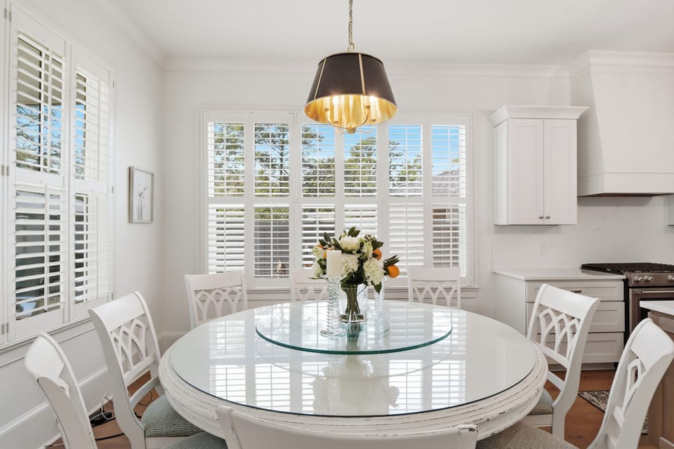 Gather around this elegant dining table where morning light filters through plantation shutters, creating the perfect setting for memorable meals with loved ones.