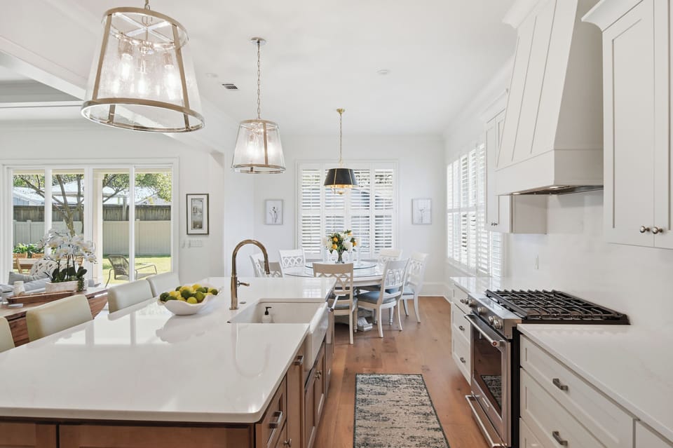 Step into your dream kitchen with gleaming countertops, professional appliances, and warm natural light streaming through elegant shutters.