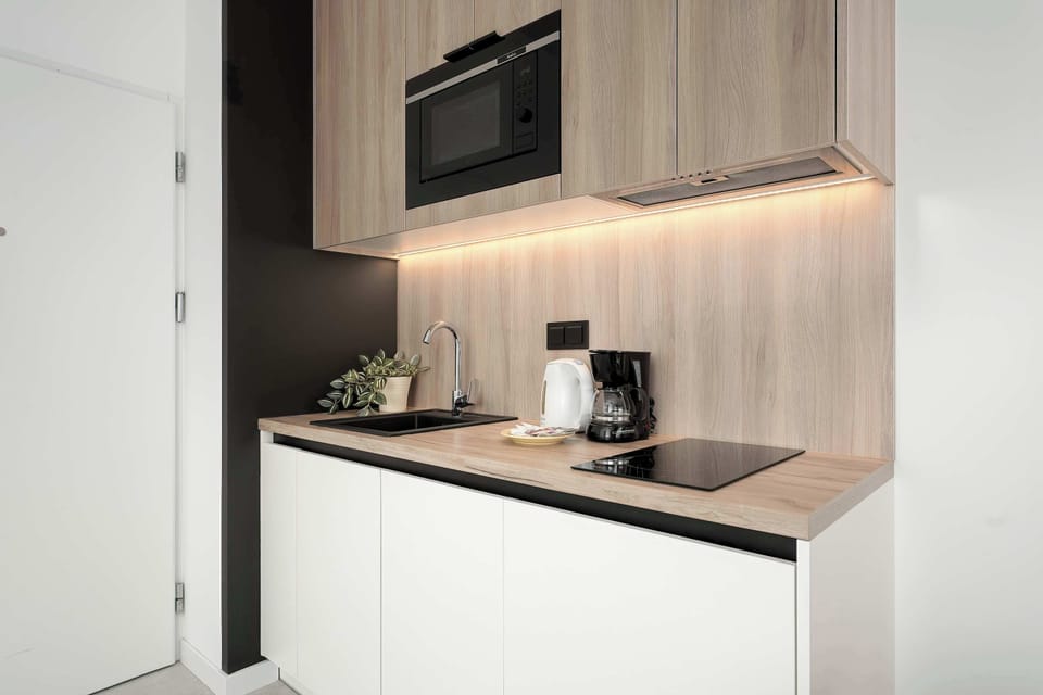 A compact kitchenette with modern cabinets, a stovetop, and essential appliances. Clean lines and neutral tones emphasize a contemporary design.