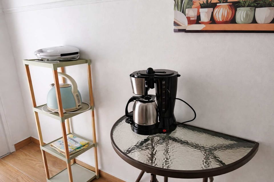 Coffee station with a coffee machine, kettle, panini press and glass table, perfect for starting the day with fresh coffee or enjoying a relaxing break indoors