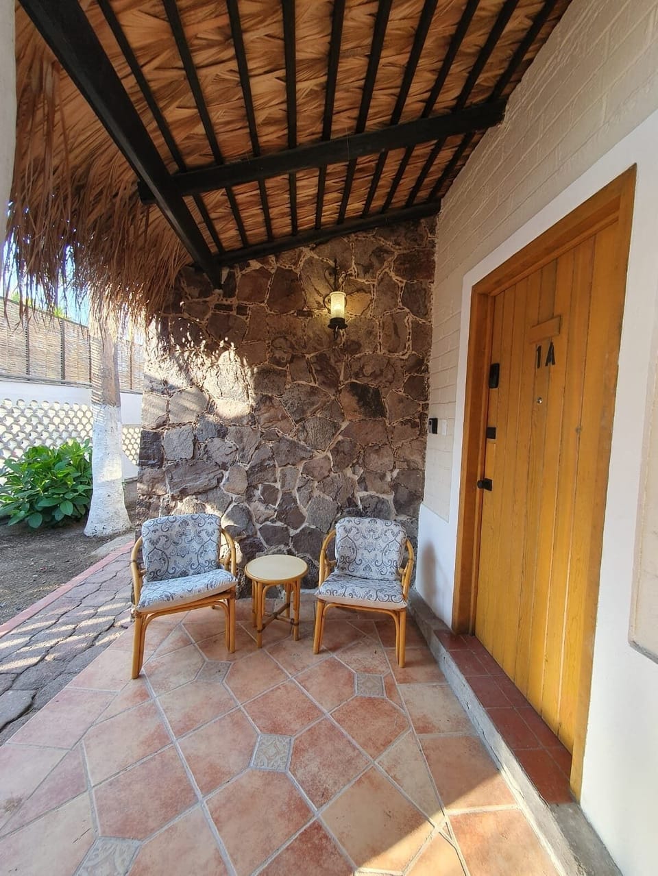 Disfruta de un momento de tranquilidad en el encantador patio de nuestras cabañas, con cómodas sillas y mesa de madera. Rodeado de paredes de piedra y bajo un techo de palma, es el lugar ideal para relajarse al aire libre.