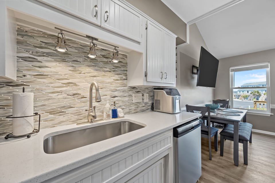 Kitchen sink area with tile backsplash and counter space