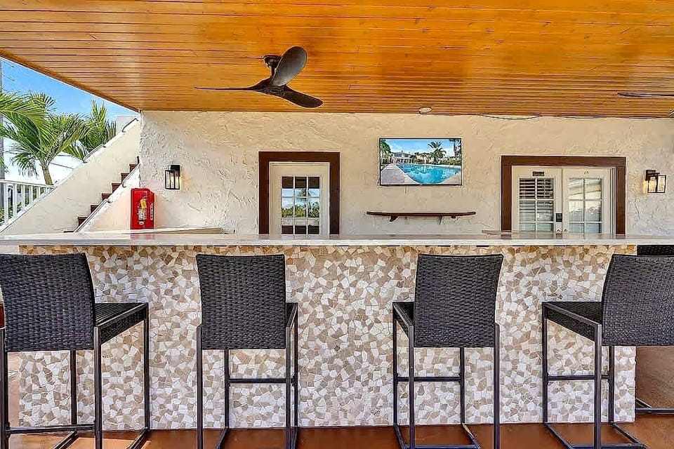 Covered poolside bar with TV and ceiling fan