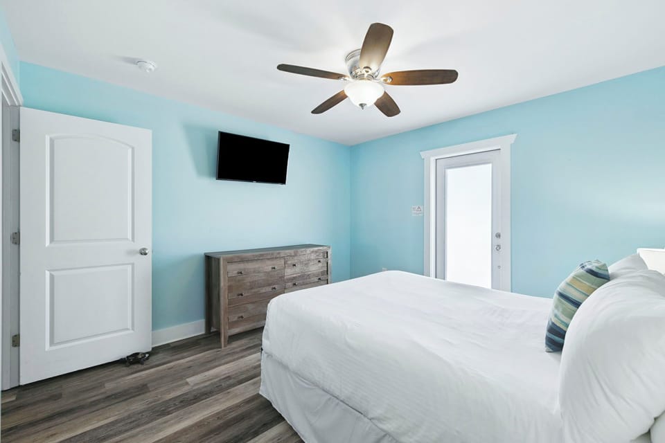 Your serene bedroom features calming blue walls, crisp white linens, and a ceiling fan for comfort.