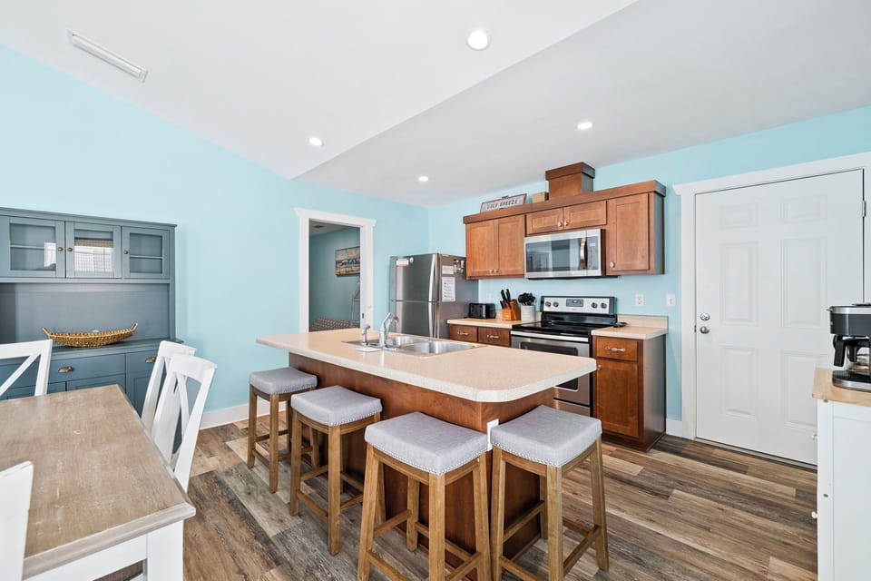 You'll love gathering around this spacious kitchen island with modern appliances and warm wood finishes in calming coastal blue tones.