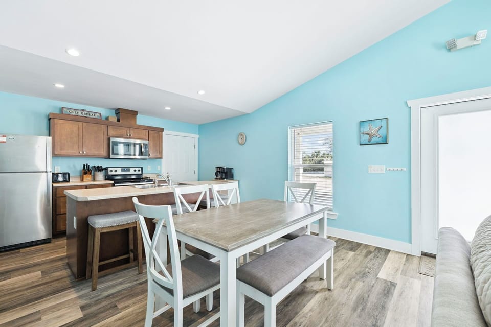 Gather around your bright coastal dining space where beach-inspired blue walls create a calming backdrop for family meals and morning coffee.