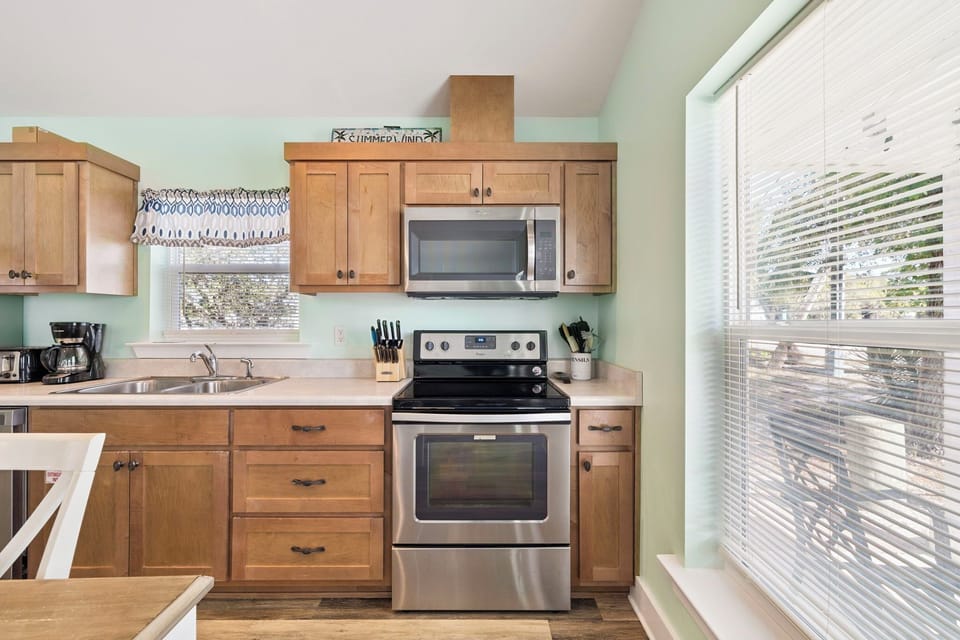 Your fully equipped kitchen awaits with warm wood cabinets, stainless appliances, and bright windows perfect for morning coffee prep.