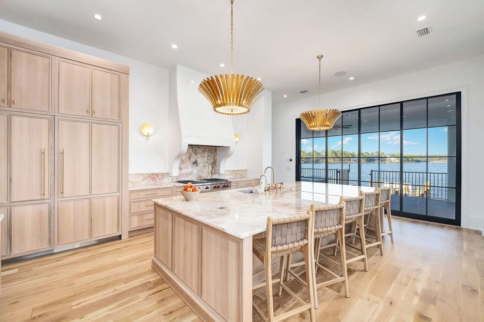 Your gourmet kitchen features marble countertops, warm wood cabinetry, and stunning lakefront views through floor-to-ceiling windows—perfect for cooking with a view.