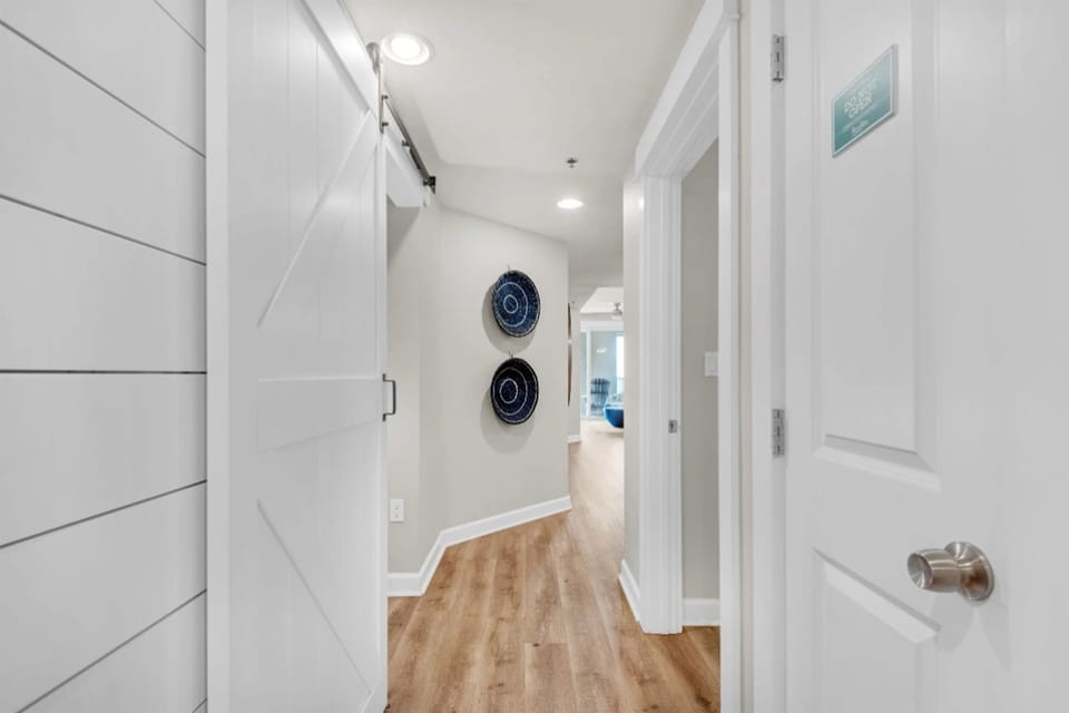 Your bright hallway welcomes you with warm hardwood floors and coastal charm, connecting you to every corner of your home away from home.