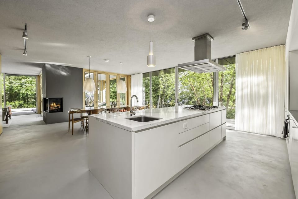 Sunlit modern kitchen with oversized island and lush greenery views