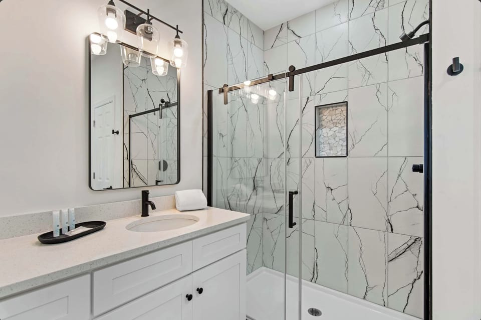 Step into your spa-like bathroom with elegant marble walls and sleek black fixtures that create a luxurious retreat.