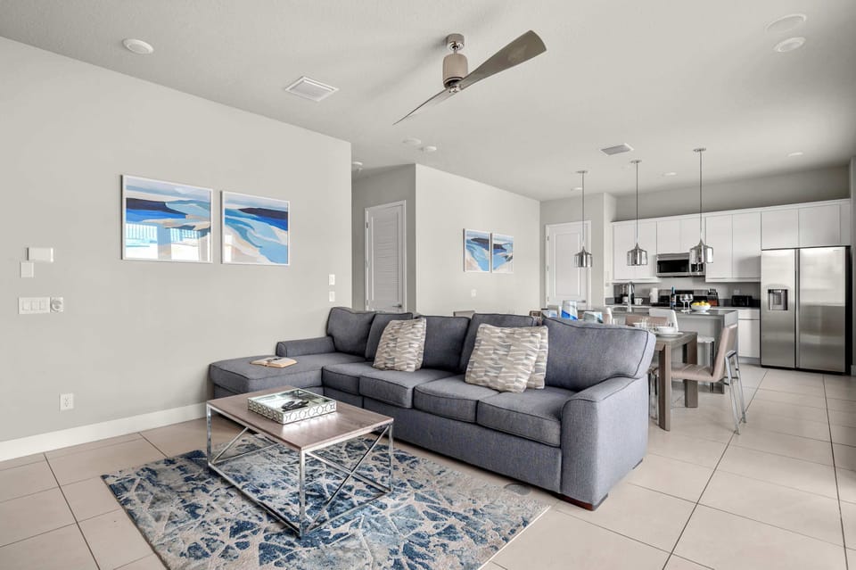 Modern open living area with a gray sectional sofa and a fully equipped kitchen.