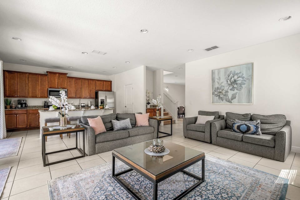 Open-concept living area with modern gray sofas and a fully equipped kitchen featuring wooden cabinetry.