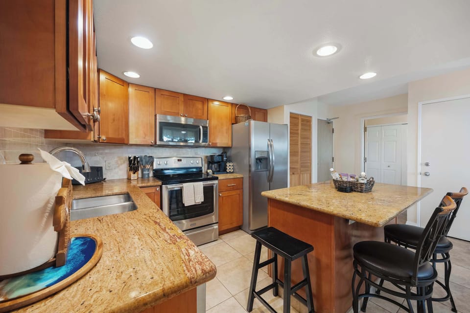 A fully appointed stainless‑steel kitchen, complete with a full‑size stove, microwave with range hood, two‑door refrigerator with freezer, and dishwasher—providing the setting for elevated meal preparation and prompt, efficient cleanup.