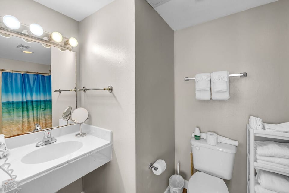 Clean and functional bathroom with vanity, fresh towels, and shower/tub combo.