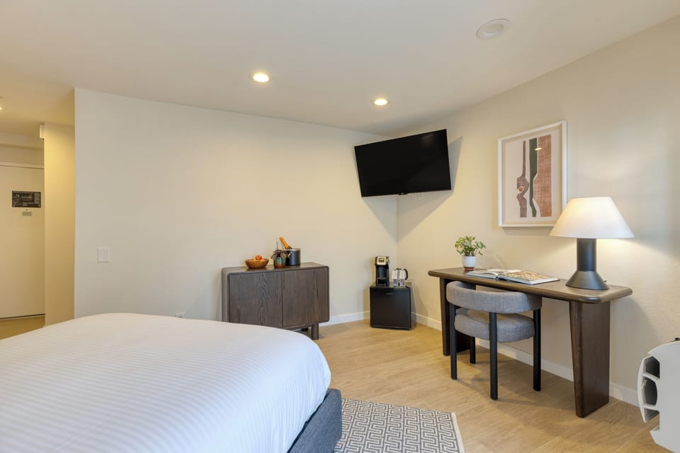 The bedroom features a plush queen bed and a TV.