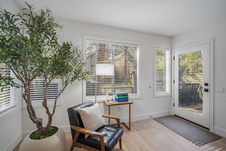 Step into your bright corner reading nook where natural light streams through modern blinds, creating the perfect spot to unwind with a book.