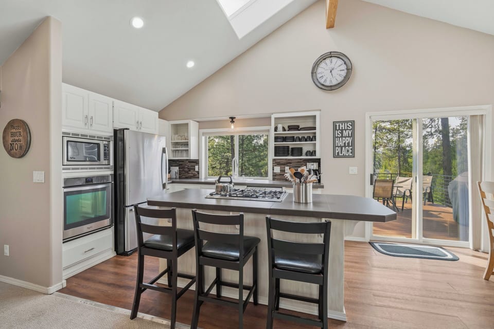 Your gourmet kitchen features a spacious island perfect for morning coffee and casual dining, with stunning forest views through every window.