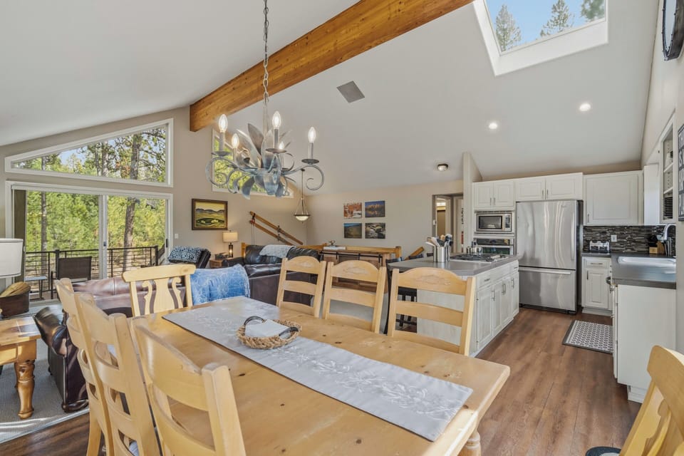 Your open-concept living space features soaring ceilings with exposed beams, panoramic forest views, and a chef's kitchen perfect for memorable meals together.
