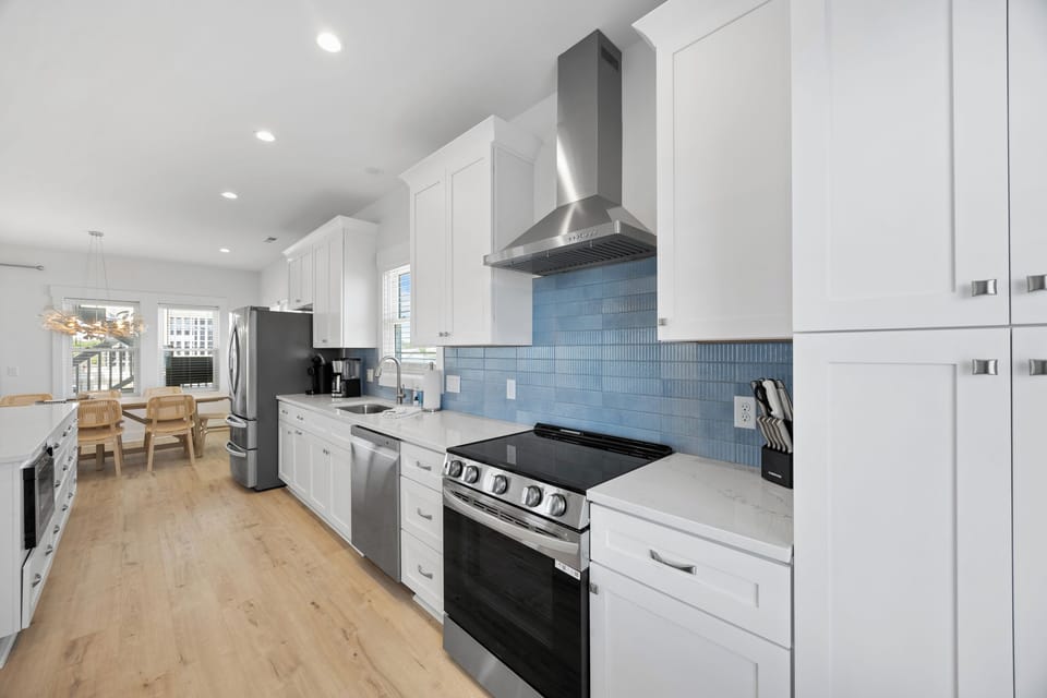Your spacious modern kitchen awaits with sleek white cabinets, stainless steel appliances, and beautiful blue tile backsplash for memorable meal preparation.
