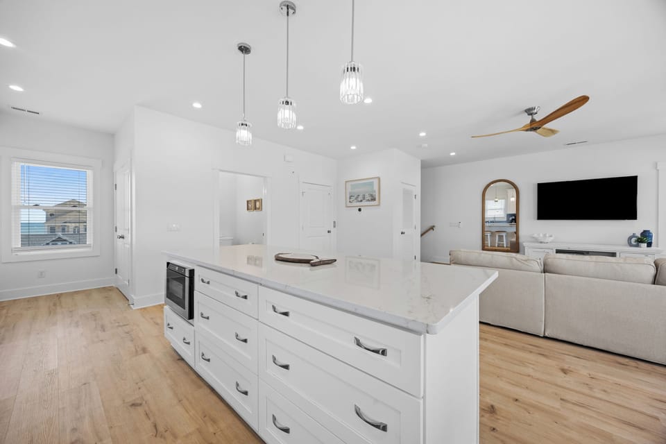 Your bright kitchen island offers ample prep space while stylish pendant lights cast a warm glow over gatherings.
