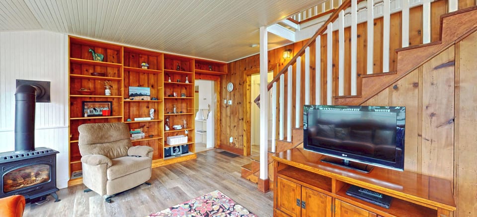 Cozy up by the fireplace in this warm living room with rich wood shelving, comfortable seating, and entertainment center.