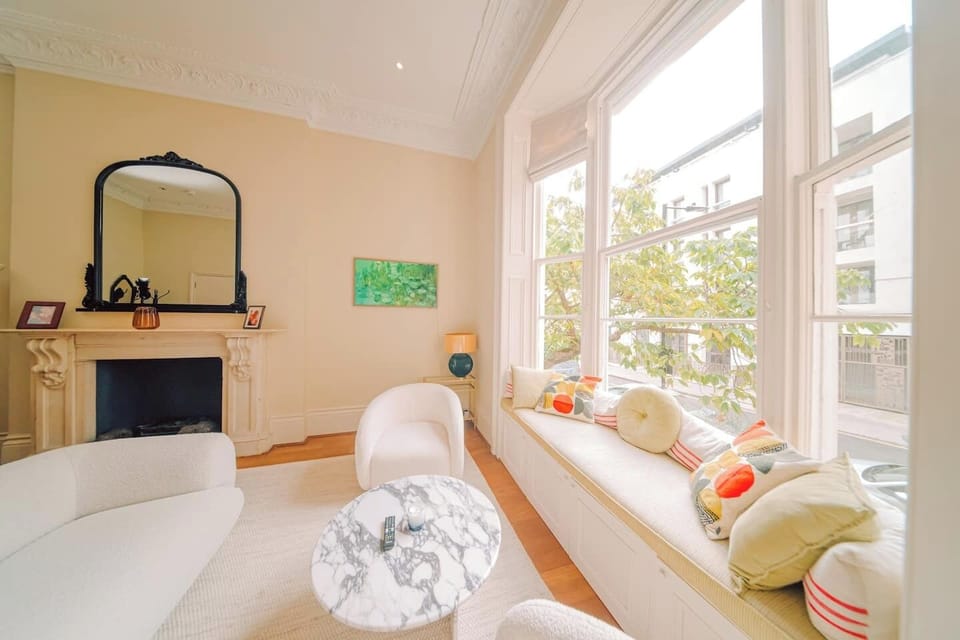 seating area with white chairs, a marble coffee table, and a window