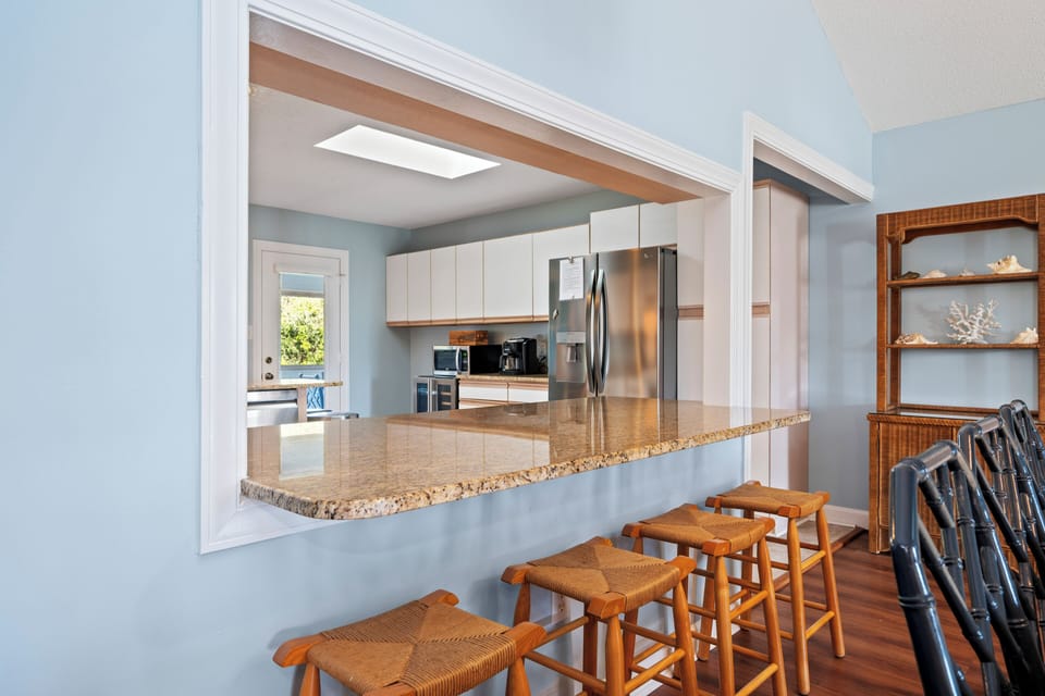 Your fully-equipped kitchen opens to a breakfast bar where morning conversations flow as easily as coffee.