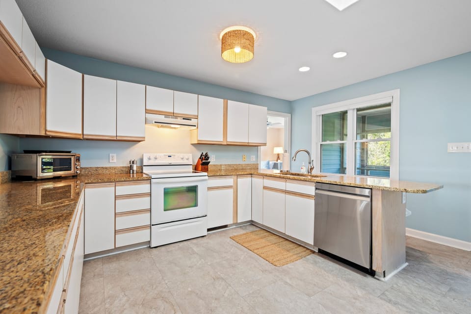 Prepare meals in this spacious kitchen with granite counters, full appliances, and warm wood accents under elegant pendant lighting.