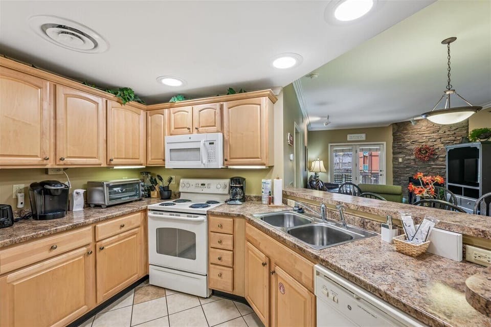 Your fully equipped kitchen features granite countertops, warm wood cabinets, and modern appliances for preparing delicious meals during your stay.