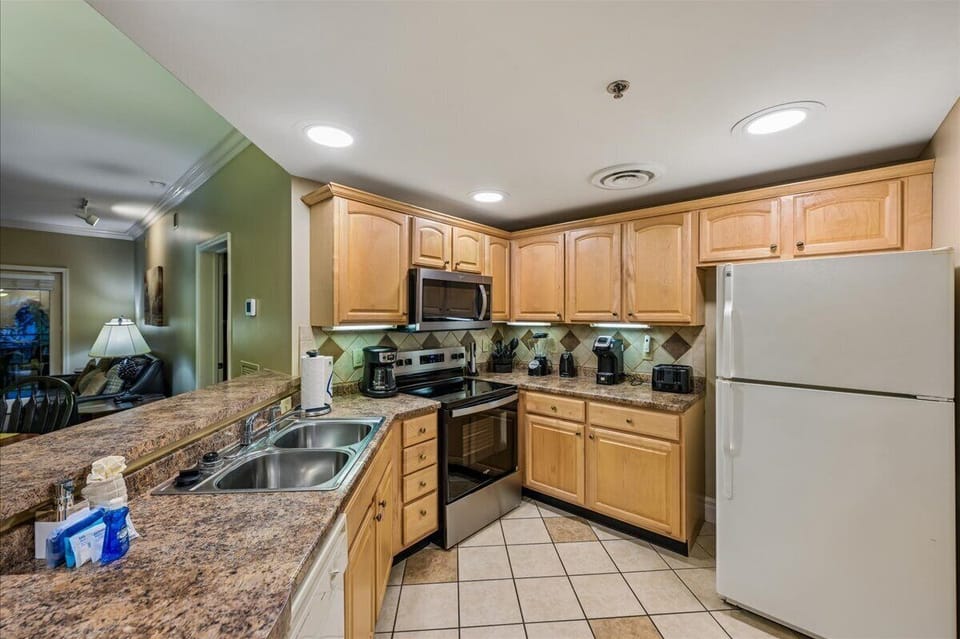 Your fully-equipped kitchen awaits with granite counters, stainless appliances, and warm wood cabinets—perfect for preparing memorable meals during your stay.