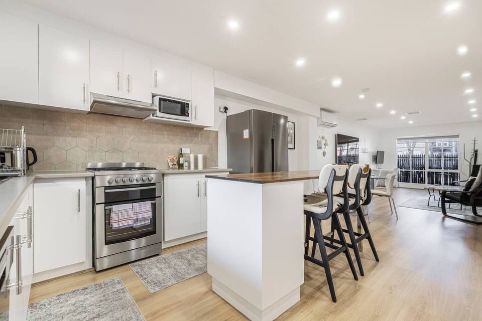 Chat over drinks at the breakfast bar as dinner sizzles on the gas cooktop in the modern kitchen.